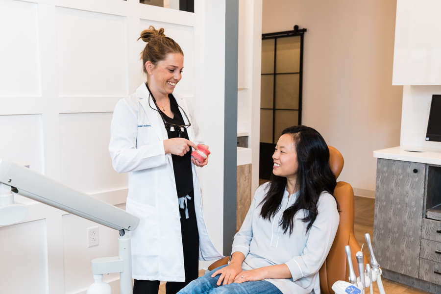 dentist holding fake teeth and talking to a patient